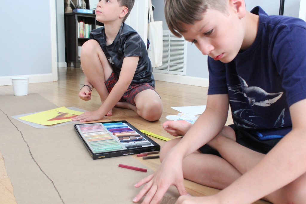 Kids sitting on floor drawing with chalk pastels