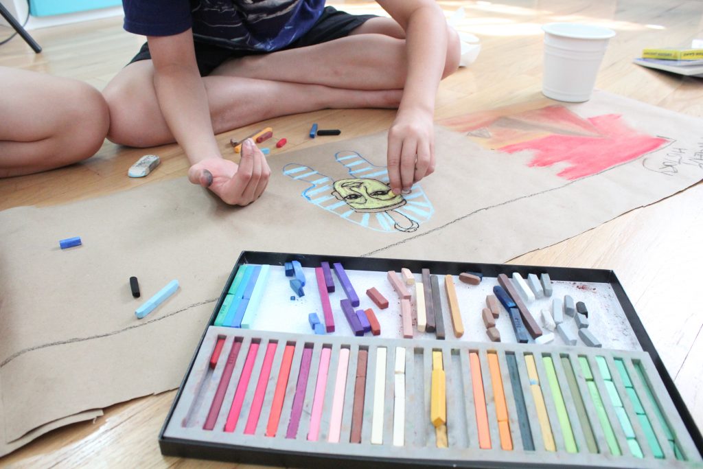 Chalk Pastels on floor with kid hands drawing 